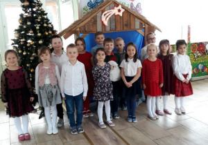 Grupa dzieci 6 - letnich na tle Szopki Bożonarodzeniowej.