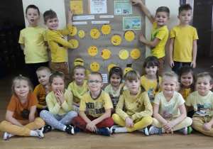 Dzieci ubrane na żółto trzymają plakat dotyczący Dnia Życzliwości.