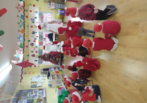 Grupa dzieci siedząca przed Mikołajem i Śnieżynką