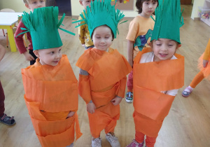 Trójka dzieci przebranych za marchewki wykonanych z pomarańczowo- zielonej bibuły
